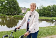 Frau mit Rollator am Wasser.