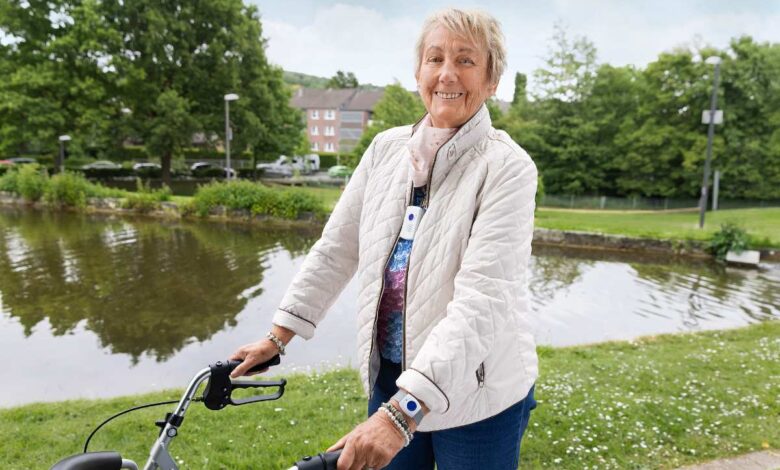 Frau mit Rollator am Wasser.